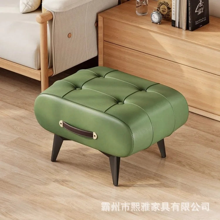 Green tufted leather low stool with black tapered legs and a side leather handle.